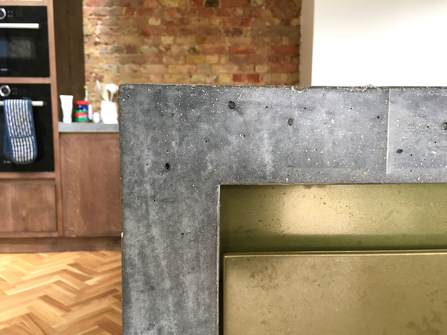 Conscious Forms - penge london large cast insitu polished concrete island with waterfall end brass doors corner detail